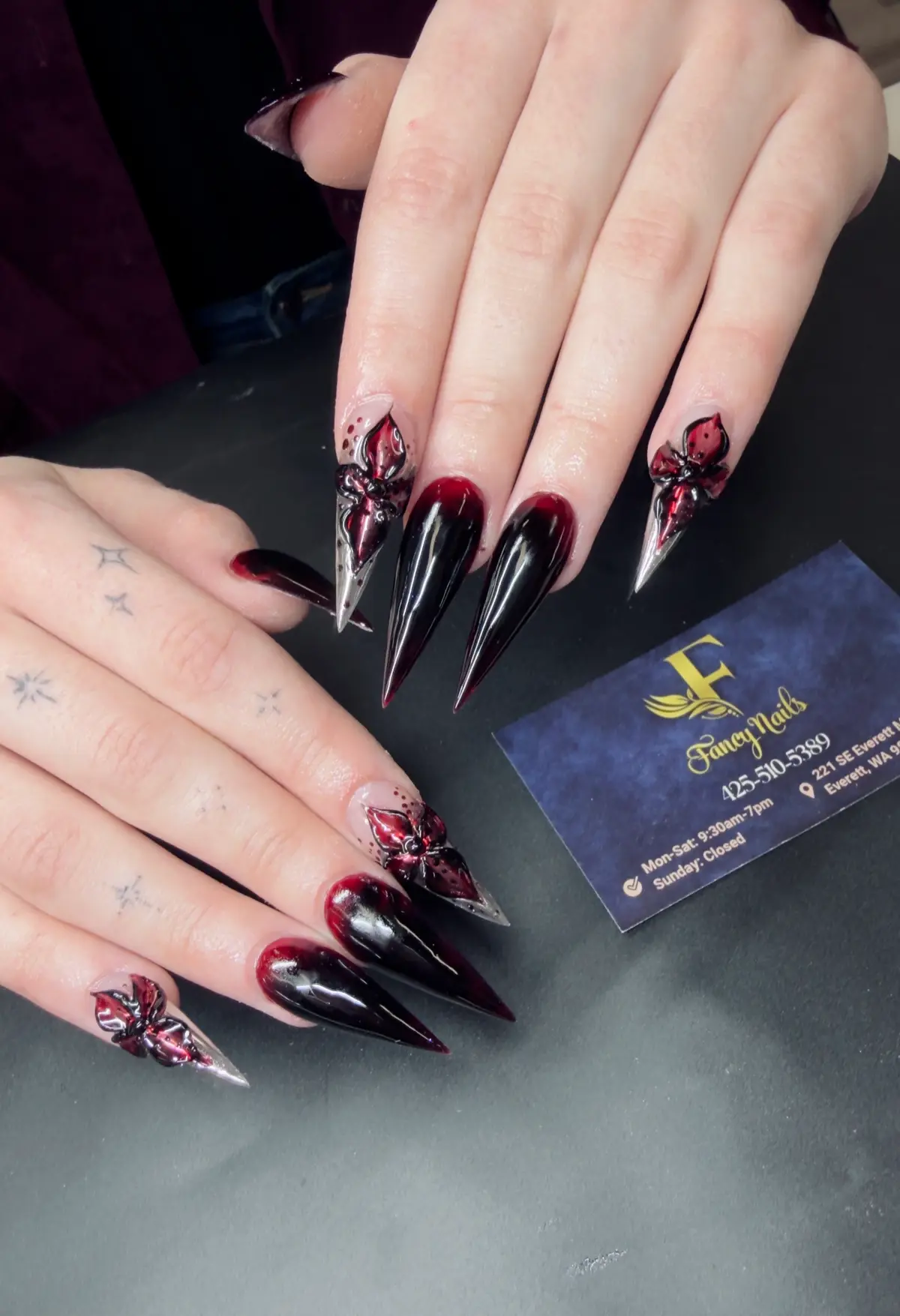 Black and deep red stiletto nails with three-dimensional floral details